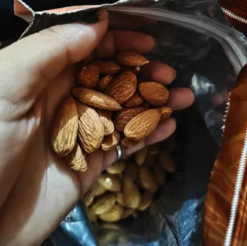 Customer photo: handful of almonds above an opened pack